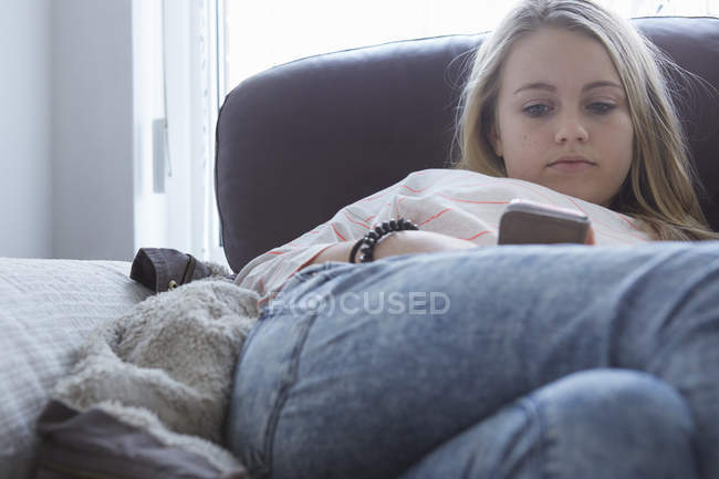 Girls reading smartphone texts on sofa — Stock Photo