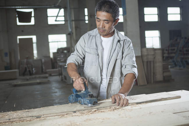 Carpenter cutting wooden plank in factory, Jiangsu, China — Stock Photo