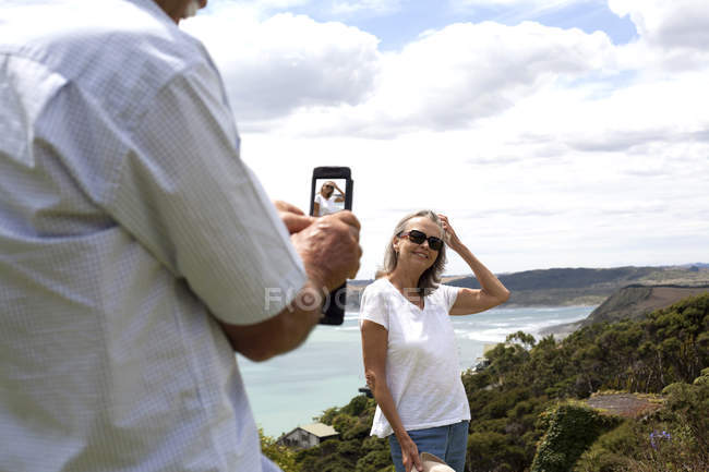 Marido fotografando esposa, oceano no fundo, Raglan, Nova Zelândia — Fotografia de Stock