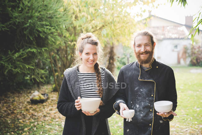Couple dans le jardin tenant des pots d'argile regardant la caméra souriant — Photo de stock