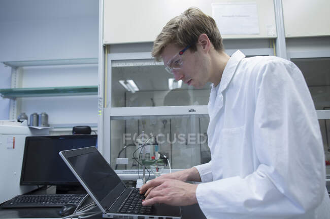 Чоловічий вчений, що друкує на ноутбуці в лабораторії — стокове фото