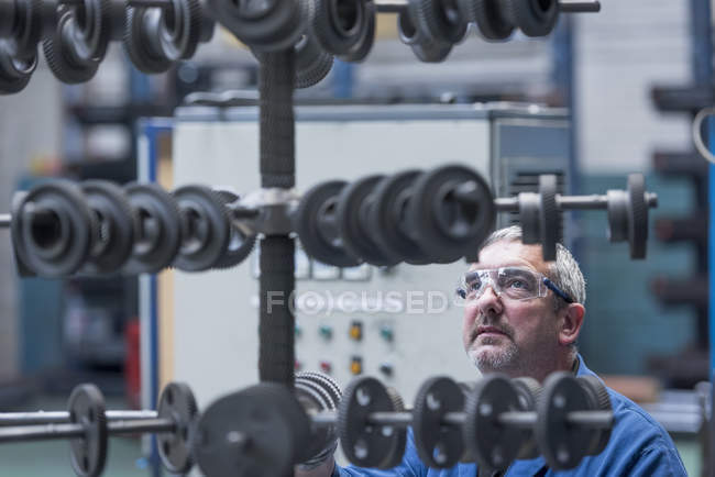 Engineer with shot blasted gear wheels in engineering factory — Stock Photo