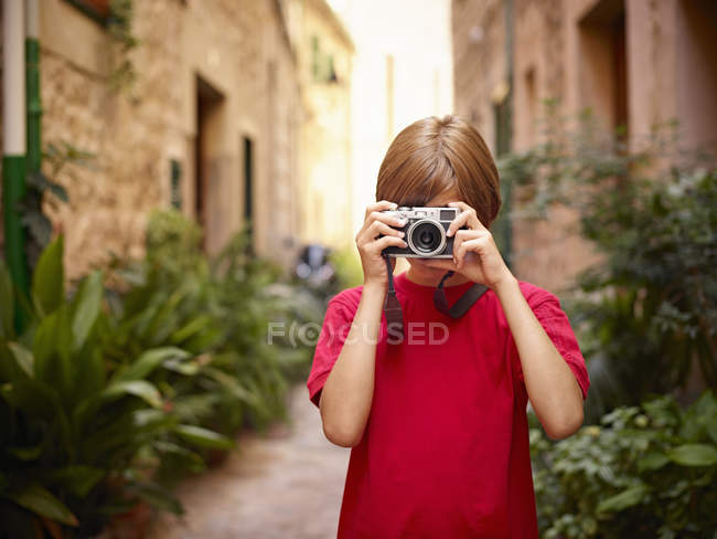 Niño fotografiando en la calle con cámara SLR, Mallorca, España - foto de stock