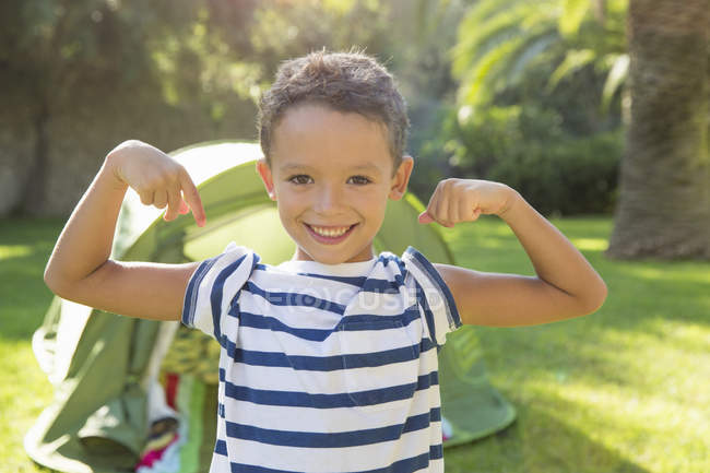 Portrait of boy in garden flexing muscles — Stock Photo