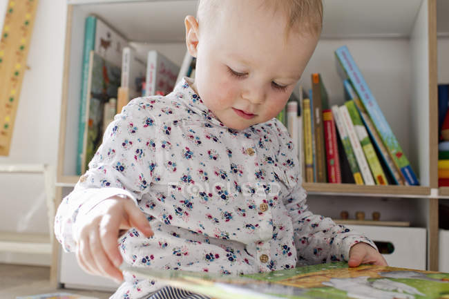 Female toddler reading book in playroom — Stock Photo