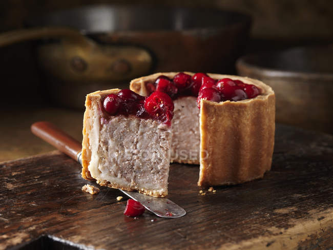 Cranberry topped pork pie on chopping board — Stock Photo