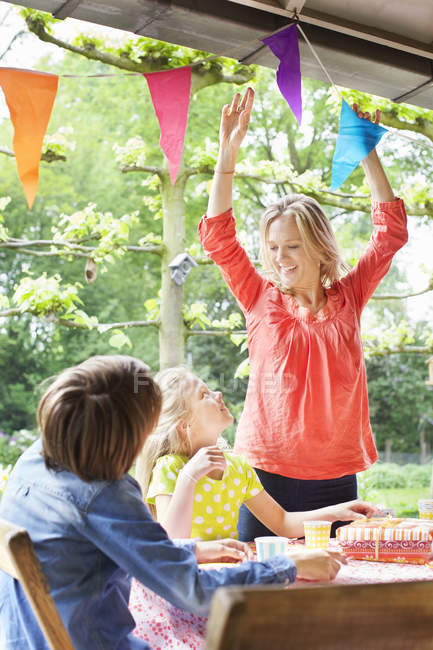 Mother chatting with children and putting up bunting — Stock Photo