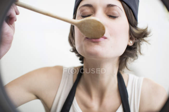Chef donna che assaggia cibo dalla casseruola in cucina commerciale — Foto stock