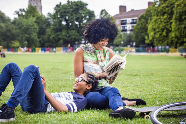 Garçon et mère relaxant et livre de lecture dans le parc — Photo de stock