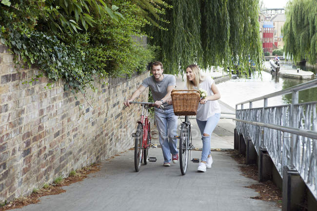 Coppia di ciclisti che spinge le bici lungo il canale, Londra, Regno Unito — Foto stock