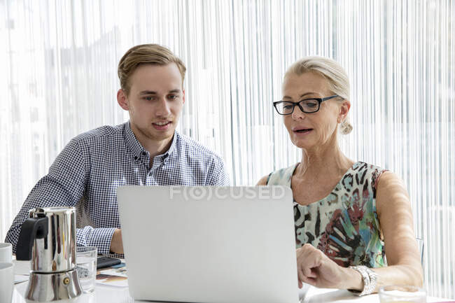 Colleagues sitting looking at laptop computer — Stock Photo