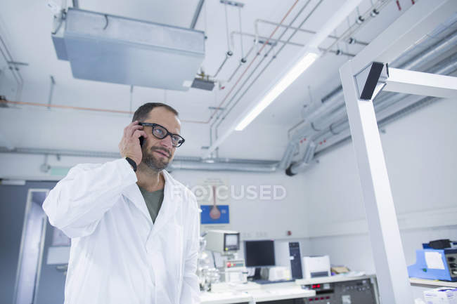 Asistente de laboratorio usando smartphone en laboratorio científico - foto de stock
