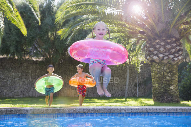Girl jumping with inflatable ring into garden swimming pool — Stock Photo