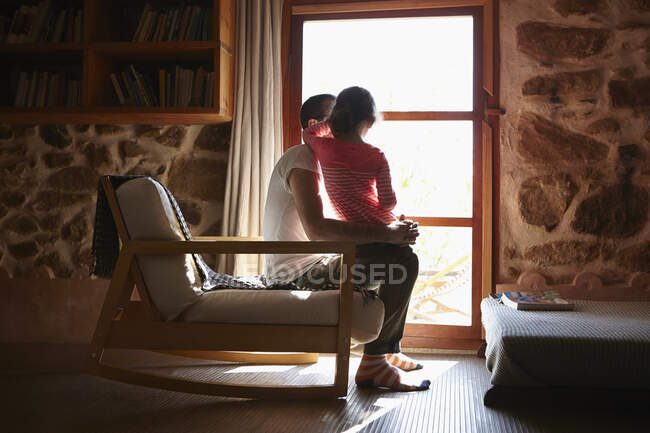 Hombre adulto y su hija mirando por la ventana - foto de stock