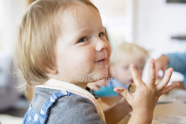 Female toddler with sticky hands at tea table — Stock Photo