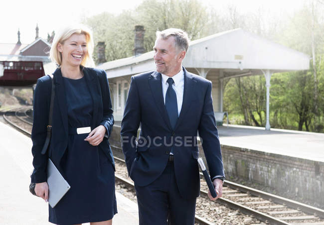 Businessman and woman talking on railway platform — Stock Photo