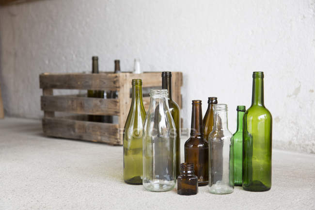 Variety of empty bottles and wooden crate in garage — Stock Photo