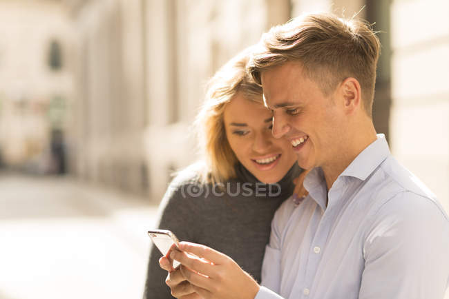 Couple partageant un message texte dans la rue — Photo de stock