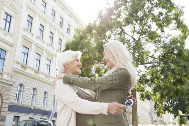 Мати і дочка, обіймати вулиці, посміхаючись — стокове фото