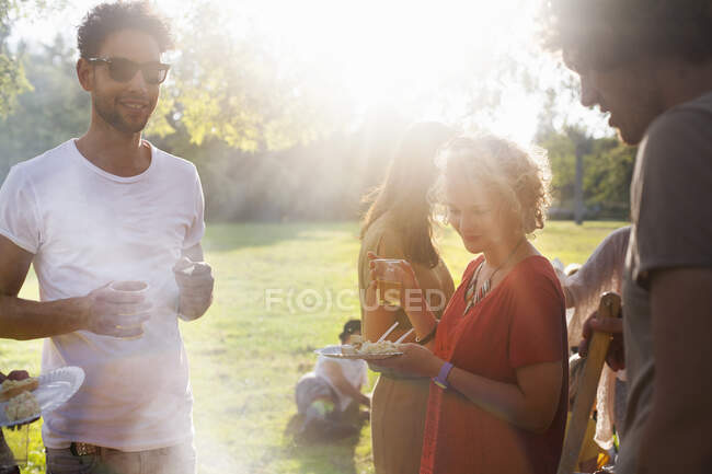 Amis adultes mangeant et buvant au coucher du soleil dans le parc — Photo de stock