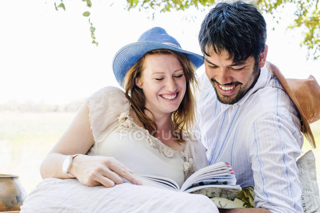 Pareja romántica leyendo guía en safari lodge - foto de stock