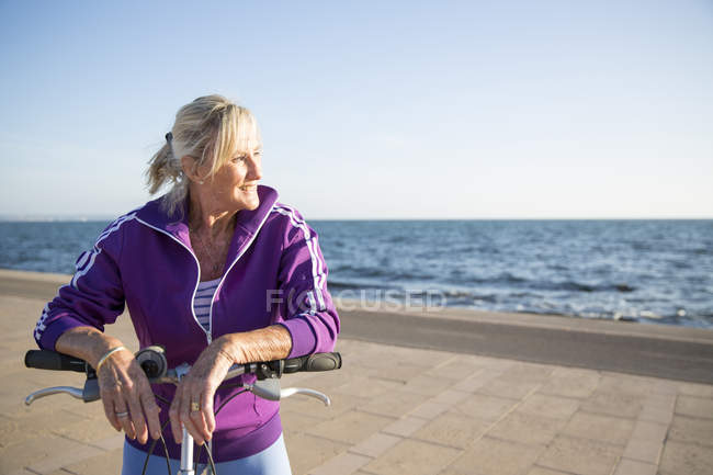 Senior mulher de bicicleta por praia — Fotografia de Stock