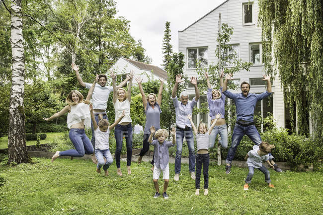 Three generational family jumping in garden — Stock Photo
