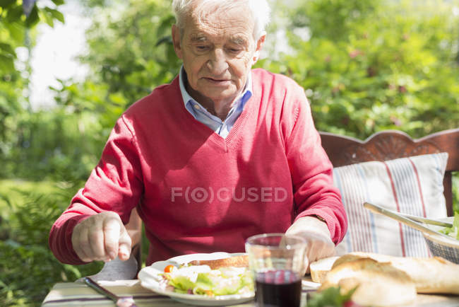 Senior man having lunch outdoors in garden — Stock Photo