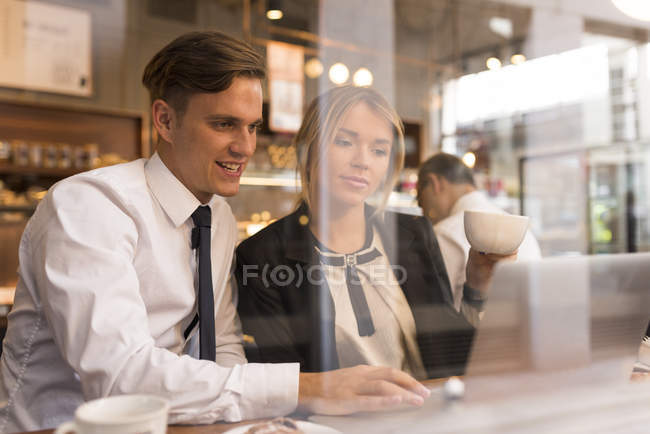 Businessman and businesswoman working on laptop in cafe — Stock Photo