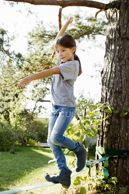Menina equilibrando na corda na árvore — Fotografia de Stock