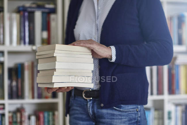 Plan recadré d'une femme portant une pile de livres dans des étagères — Photo de stock