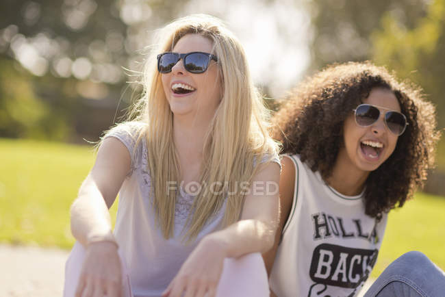 Две юные подруги смеются в парке — стоковое фото