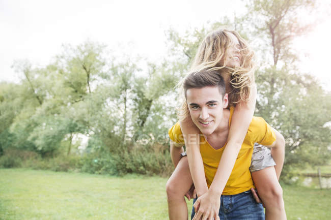 Jovem carregando jovem mulher nas costas, ao ar livre — Fotografia de Stock