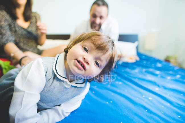 Portrait of female toddler with parents on bed — Stock Photo