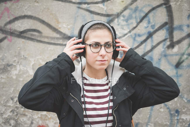 Adolescente com fones de ouvido por parede de grafite — Fotografia de Stock
