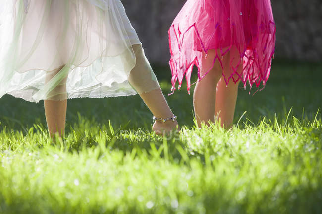 Обрізаний знімок ніг двох дівчат у казковому костюмі в саду — стокове фото