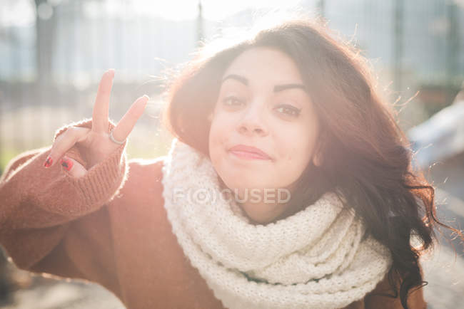 Porträt einer jungen Frau, die im Park Friedenszeichen macht — Stockfoto
