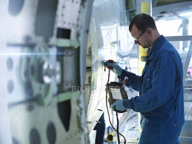 Engenheiro que utiliza equipamentos de teste não destrutivos na fuselagem de aeronaves na fábrica de manutenção de aeronaves — Fotografia de Stock