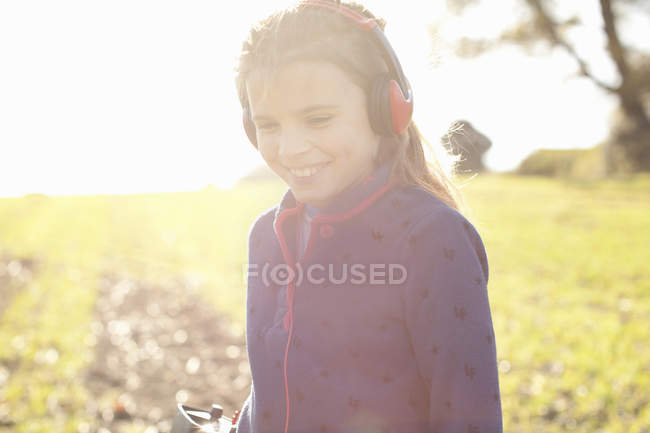 Chica sonriente con auriculares de detección de metales en el campo - foto de stock