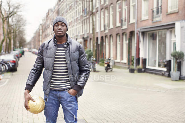 Portrait of young man on street holding soccer ball, Amsterdam, Netherlands — Stock Photo