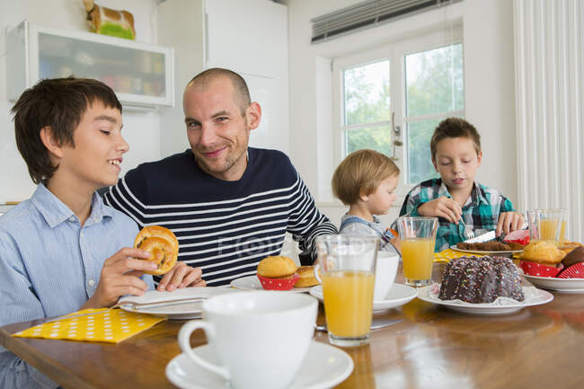 Чоловік середнього віку та сім'я мають чай за кухонним столом — стокове фото