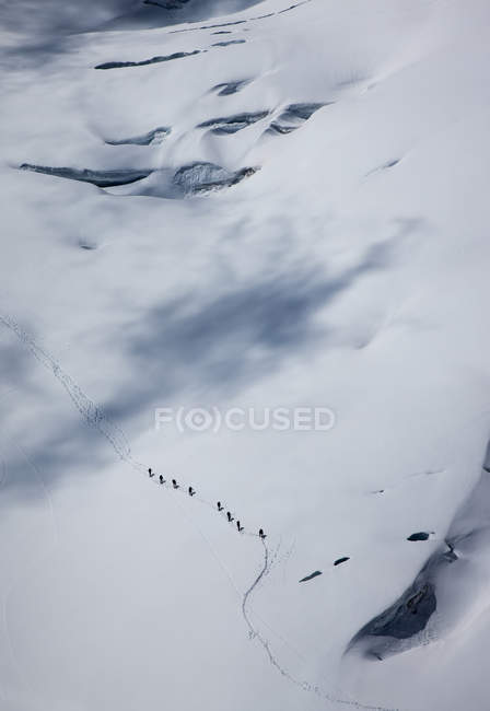 Vista lejana de alto ángulo del equipo de escalada que cruza el glaciar en Mont Blanc, Chamonix, Alta Saboya, Francia - foto de stock