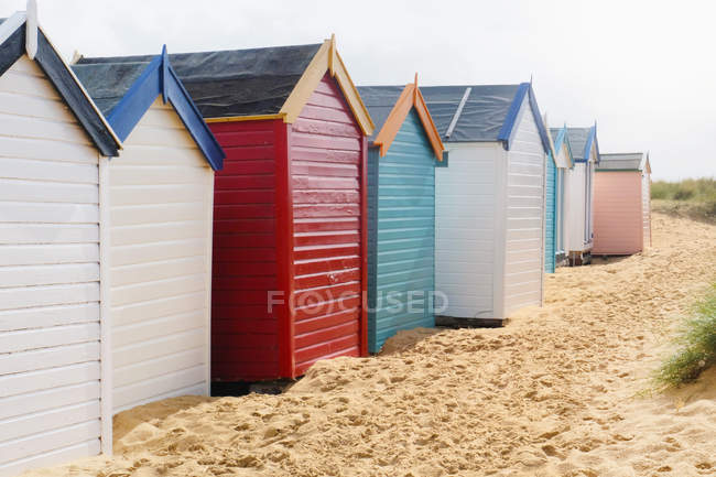 Row Of Multi Colored Beach Huts On Sand Small Buildings Sun Row Of Multi Colored Beach Huts On Sand Stock Photo