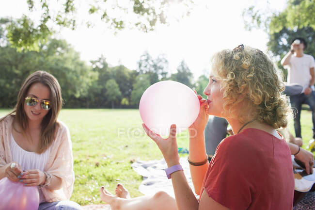 Молода жінка дме повітряну кулю на вечірці парку — стокове фото