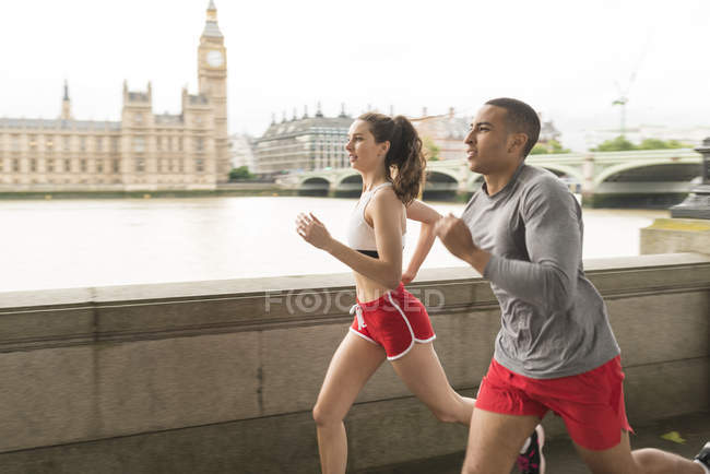 Male and female runners running along Southbank, London, UK — Stock Photo