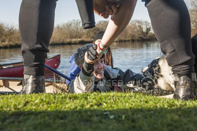 Человек, помогающий женщине среднего возраста выбраться из озера — стоковое фото