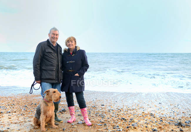 Retrato de pareja mayor con perro en la playa - foto de stock