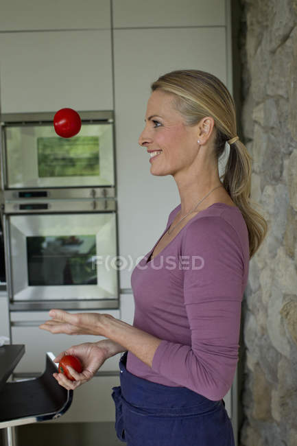 Side view of Mature woman juggling tomatoes — Stock Photo