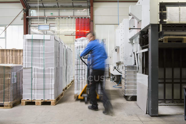 Factory worker operating pallet jack — Stock Photo