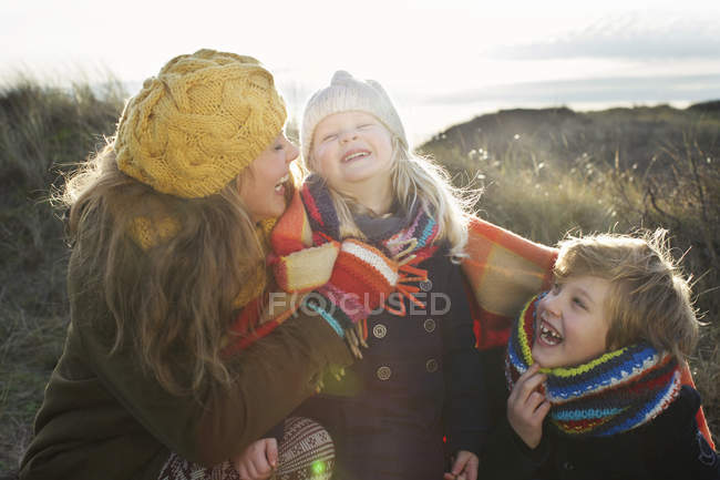Середня доросла жінка в піщаних дюнах з сином і дочкою, загорнута в ковдру — стокове фото